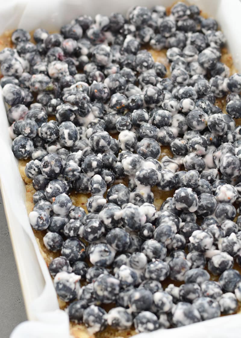 Raw blueberry filling atop an almond crust in a baking dish