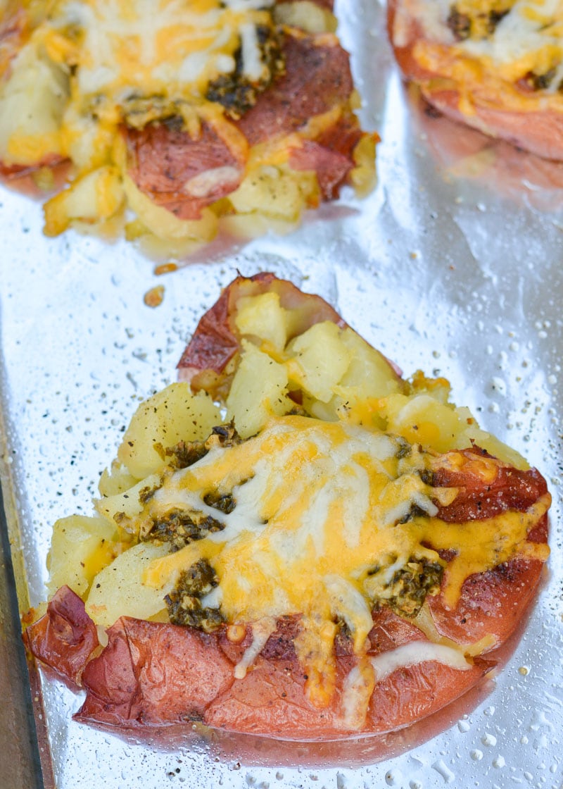 Combine four simple ingredients to make crispy, crunchy smashed potatoes! These smashed potatoes are tender on the inside, crispy on the outside and smothered with pesto and cheese for the perfect easy side dish