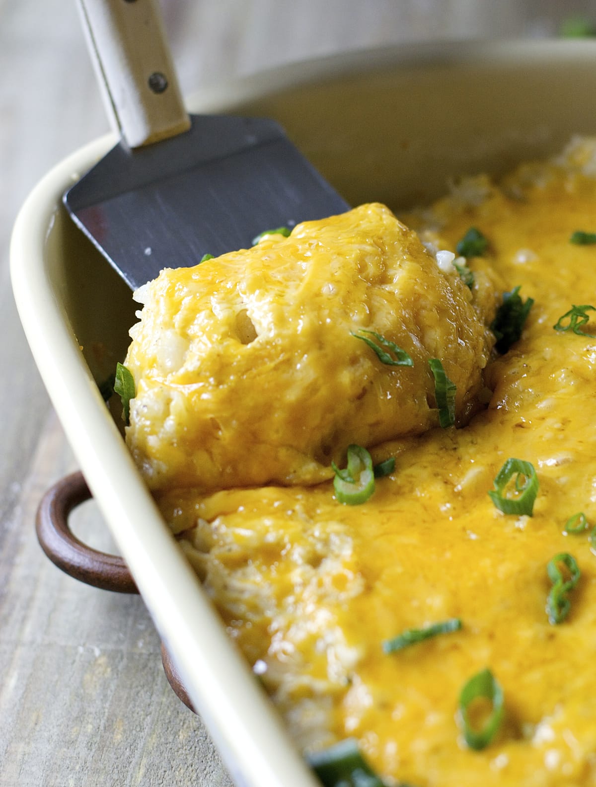 slice of cheesy chicken and rice casserole being lifted out of a baking dish