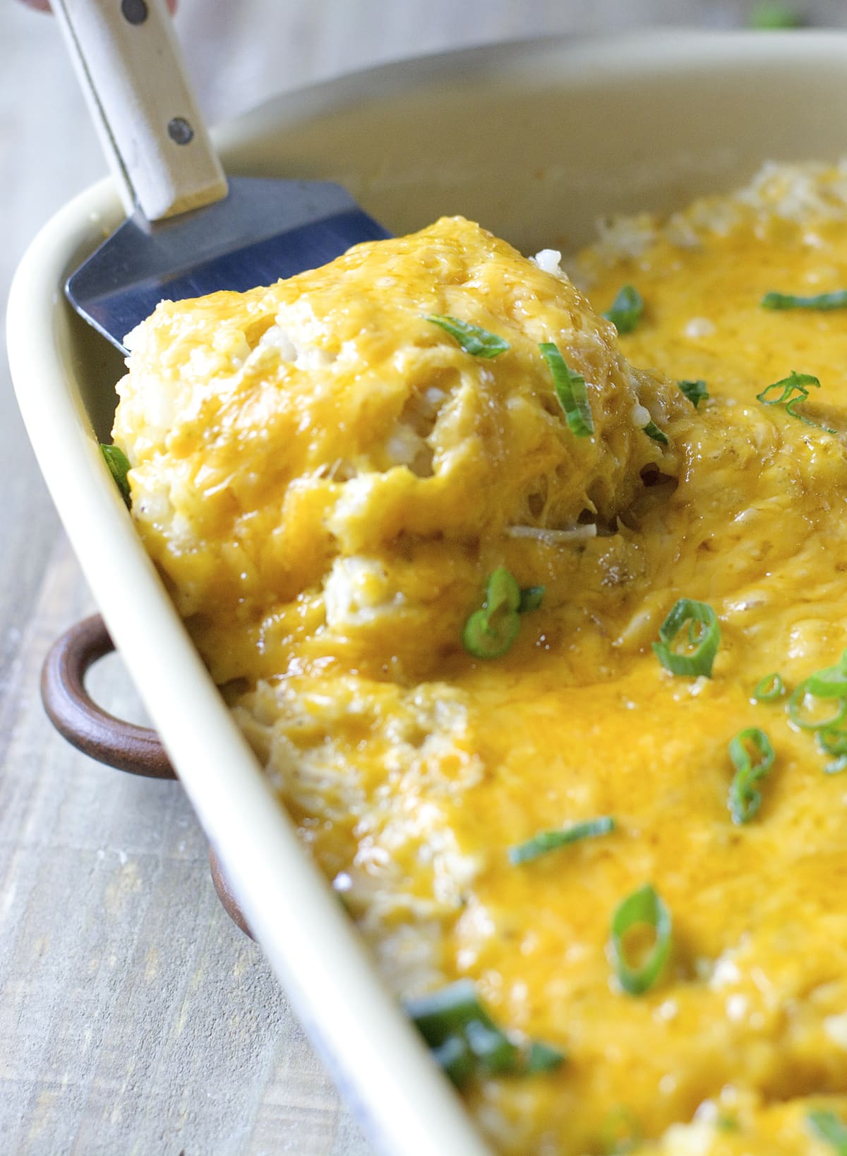 slice of cheesy chicken casserole being lifted out of a baking dish