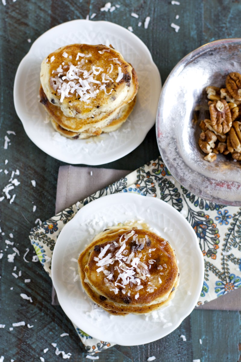 overhead view of two stacks of buttermilk chocolate chip pancakes on white plates. 