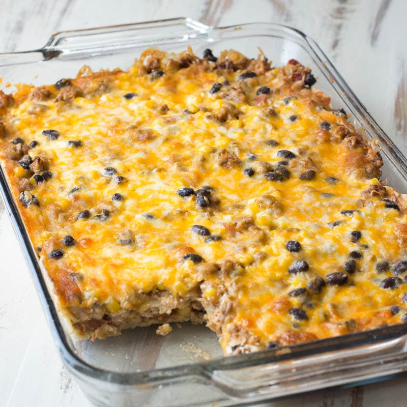 pan of taco lasagna with tortillas with a slice missing 