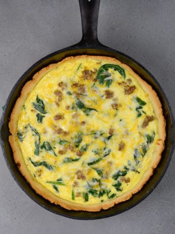 a cast iron skillet filled with the perfect sausage spinach quiche