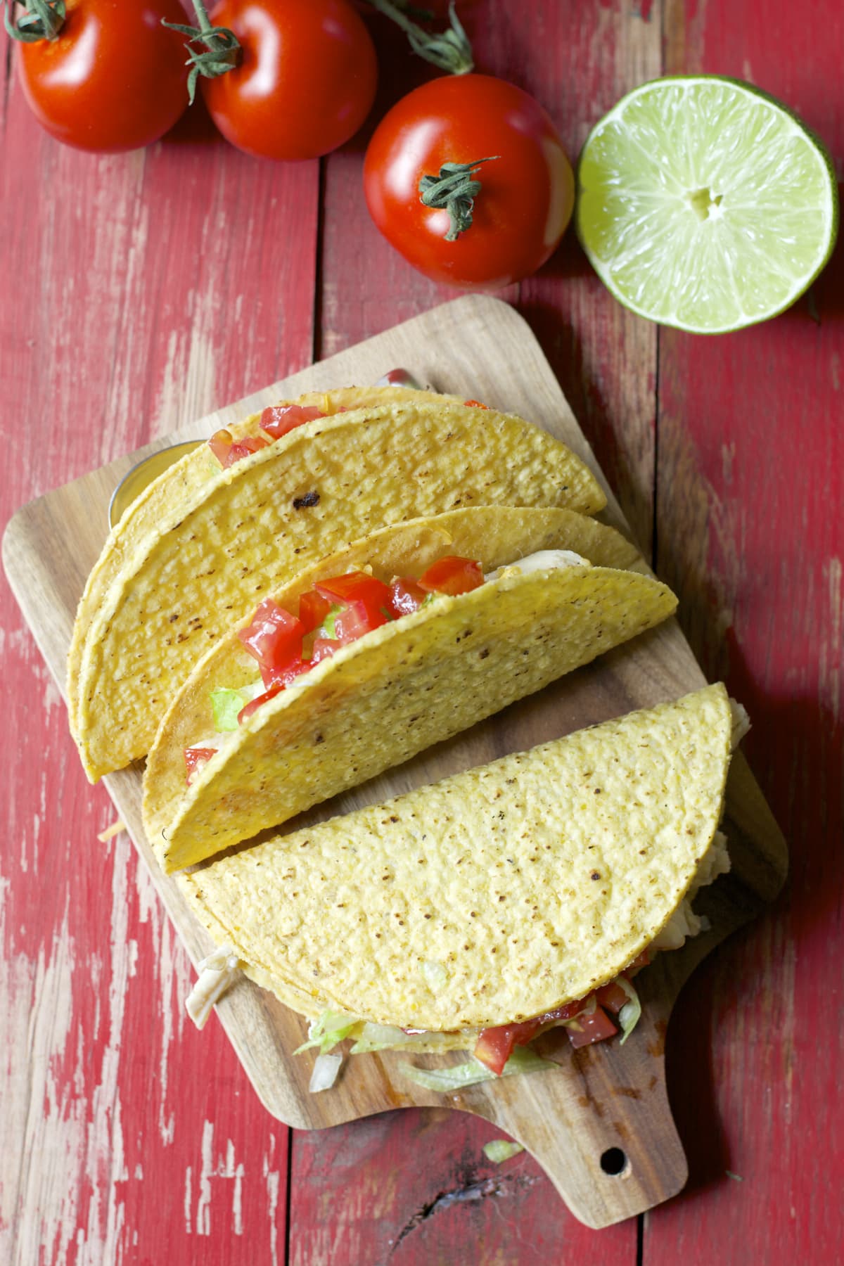 overhead view of three Crockpot shredded chicken tacos on a wood serving platter 