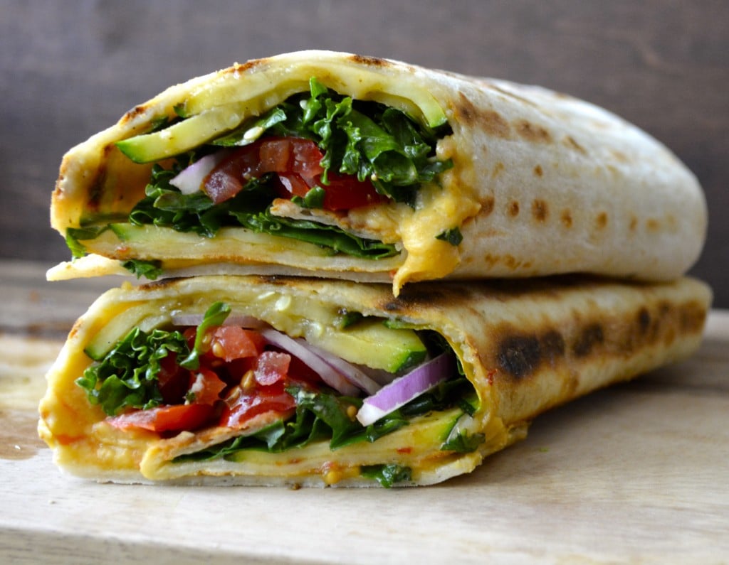 two veggie hummus wraps stacked on top of each other 