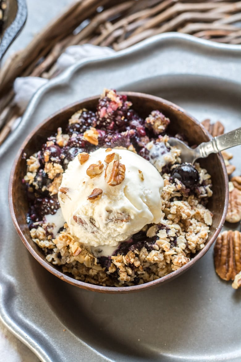 a portion of mixed berry crisp topped with ice cream in a bowl 