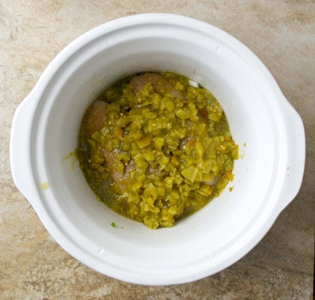 overhead view of uncooked chicken chili verde ingredients in crockpot 