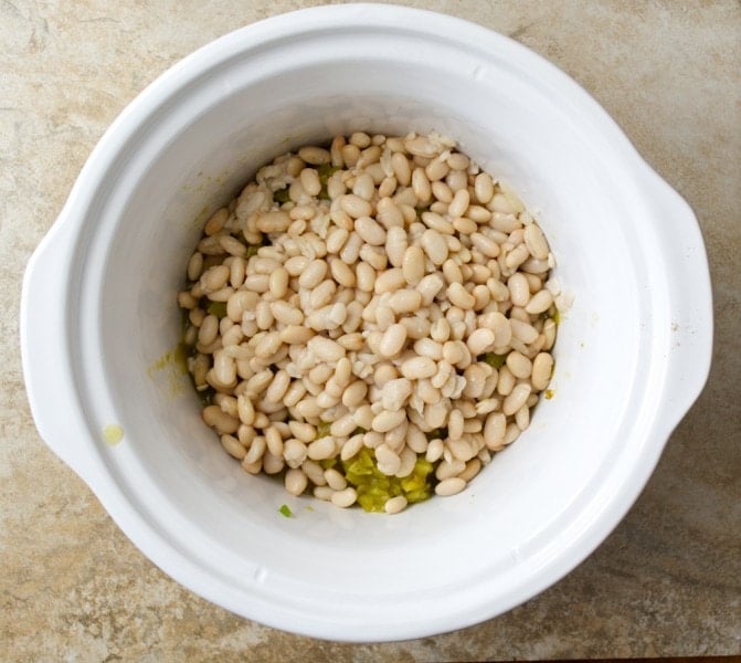 overhead view of uncooked white bean chili ingredients in crockpot 