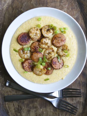 Jerk Shrimp and Andouille Sausage are cooked to perfection and laid on a bed of ultra creamy cheddar grits for the ultimate Southern meal!