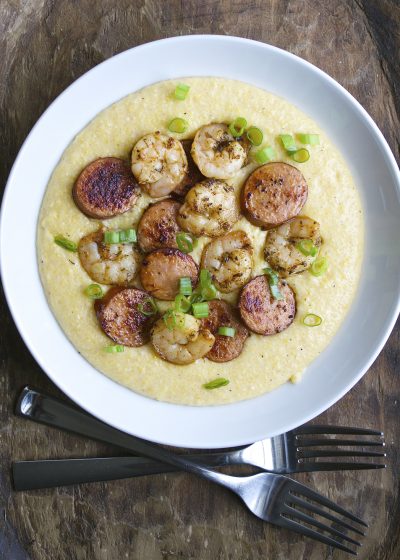 Jerk Shrimp and Andouille Sausage are cooked to perfection and laid on a bed of ultra creamy cheddar grits for the ultimate Southern meal!