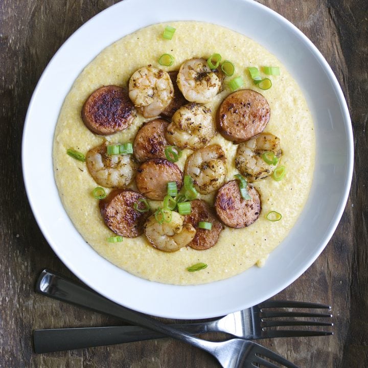 Jerk Shrimp and Andouille Sausage are cooked to perfection and laid on a bed of ultra creamy cheddar grits for the ultimate Southern meal!