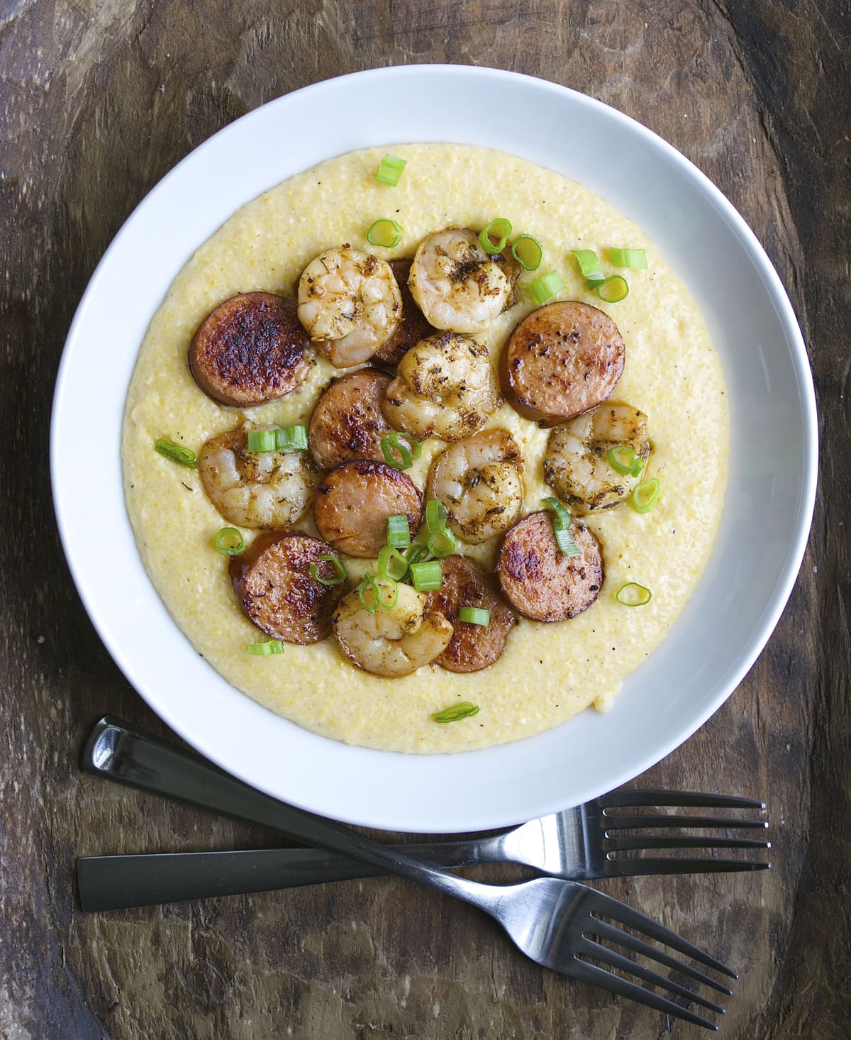 Jerk Shrimp and Andouille Sausage are cooked to perfection and laid on a bed of ultra creamy cheddar grits for the ultimate Southern meal!