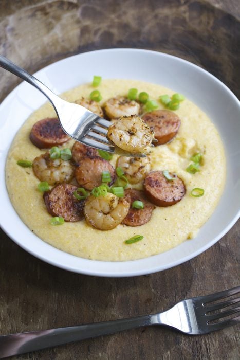 Jerk Shrimp and Andouille Sausage are cooked to perfection and laid on a bed of ultra creamy cheddar grits for the ultimate Southern meal!