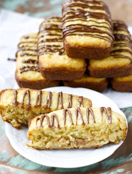 A pyramid of the best gluten free banana bread loaves. One is one a plate in front and has been cut in half to show filling. 