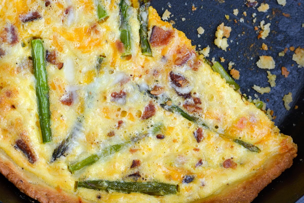 Overhead view of a bacon asparagus quiche in a cast iron skillet. 
