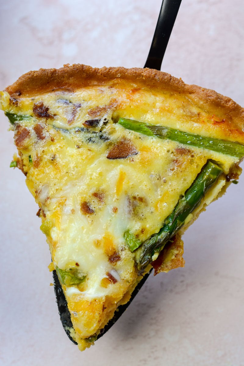 A slice of asparagus, bacon and cheddar quiche. 