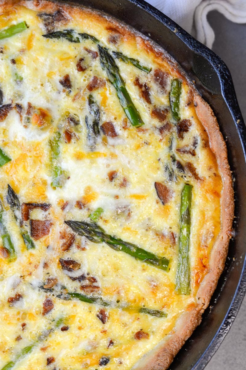 Overhead view of a bacon asparagus quiche in a cast iron skillet. 