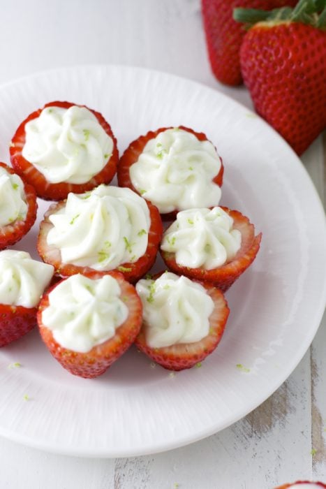 Overhead view of key lime cream cheese stuffed strawberries on a white plate. 