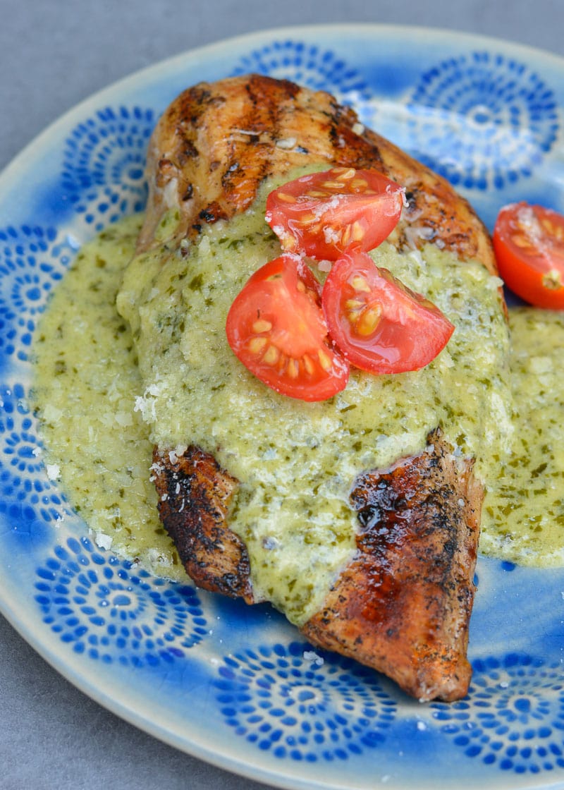 This Chicken with Pesto Cream Sauce is low carb comfort food at it's finest! Grilled Garlic Chicken is smothered with a Creamy Pesto Alfredo sauce making it a decadent keto-friendly dinner!