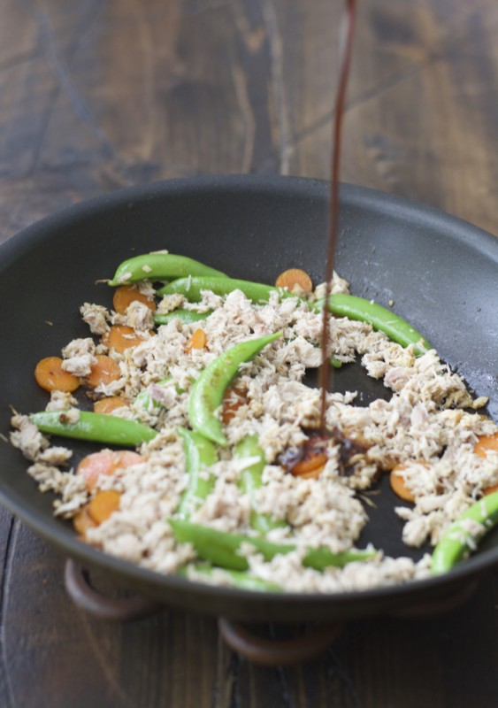 soy sauce being poured into a skillet with tuna and veggies 