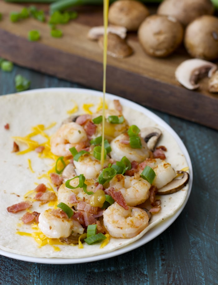 Honey mustard being drizzled over an open homemade shrimp quesadilla. 