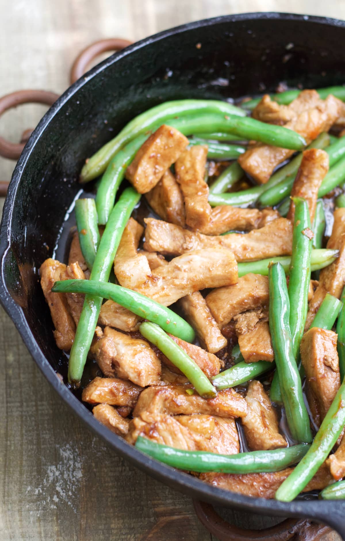 Green beans and sesame pork stir fry in a cast iron skillet. 