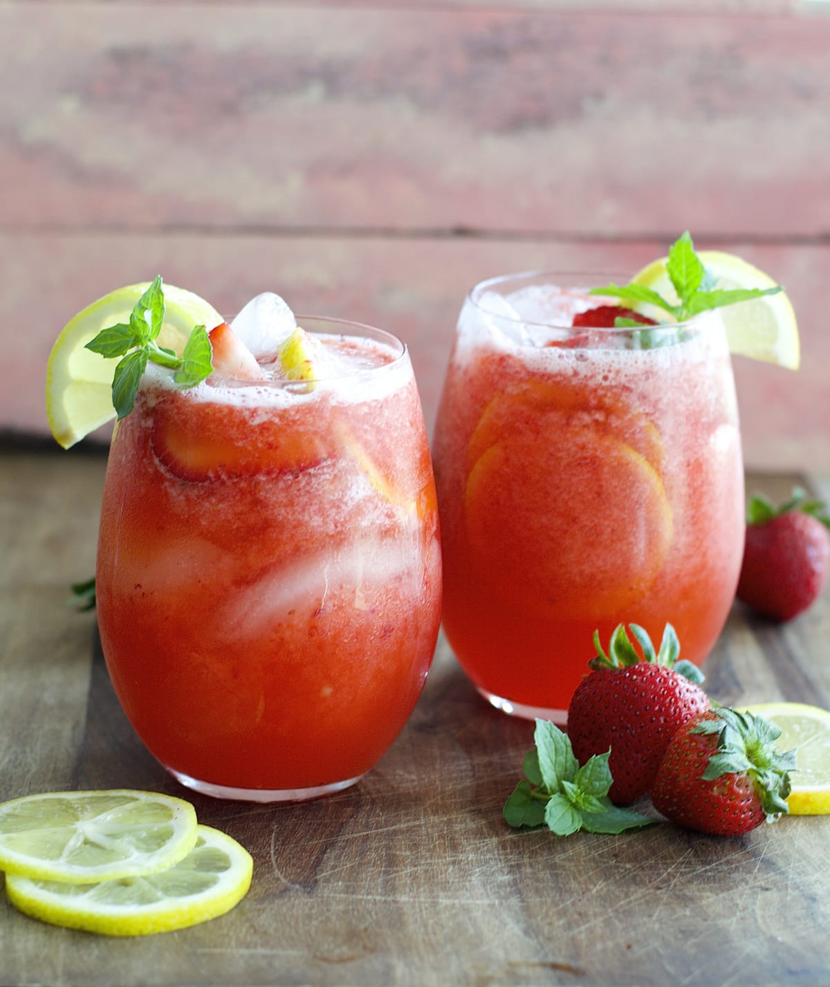 two glasses of blended strawberry lemonade on a countertop