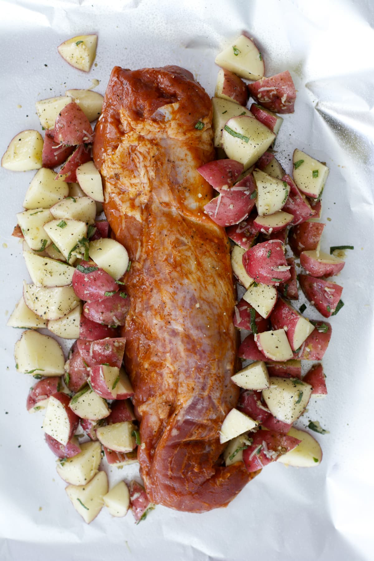 overhead view of raw pork loin and potatoes in foil 