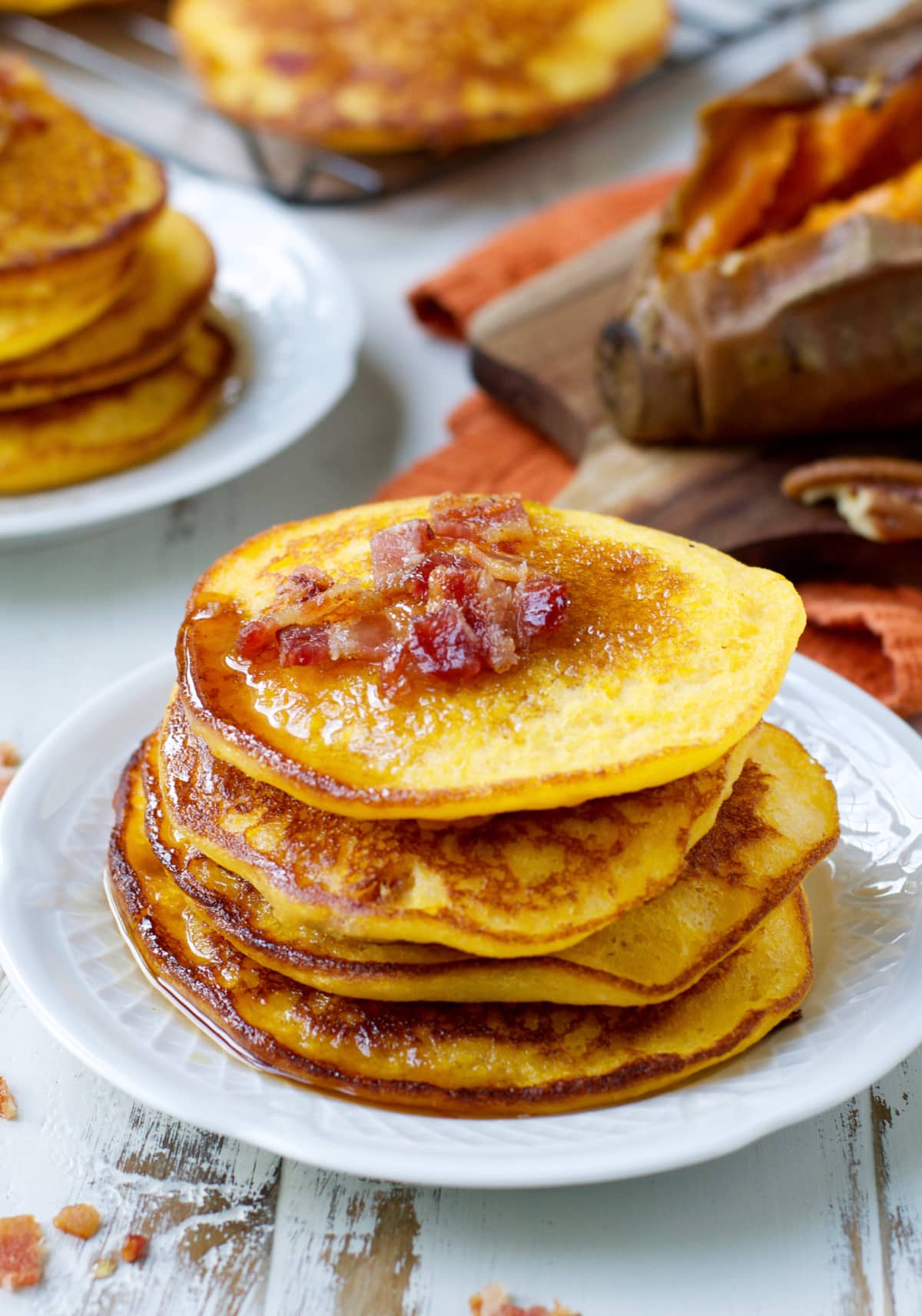 sweet potato and bacon pancakes stacked on a white plate 