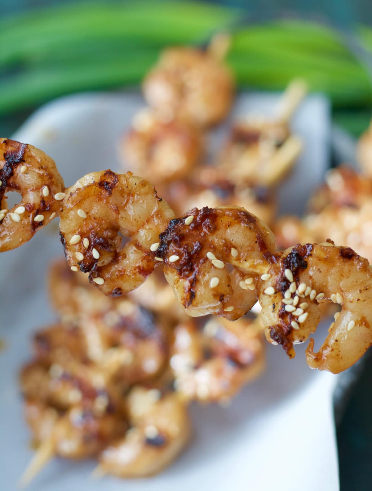 a sesame shrimp skewer being held aloft 