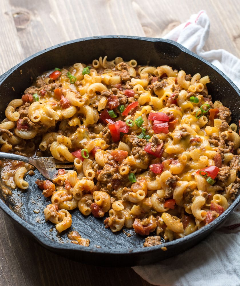 taco mac and cheese in a cast iron skillet. A portion has already been scooped out. 