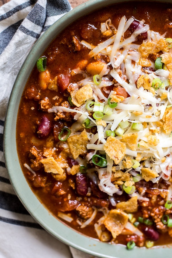 bowl of ground turkey chili topped with Fritos, cheese, and green onions