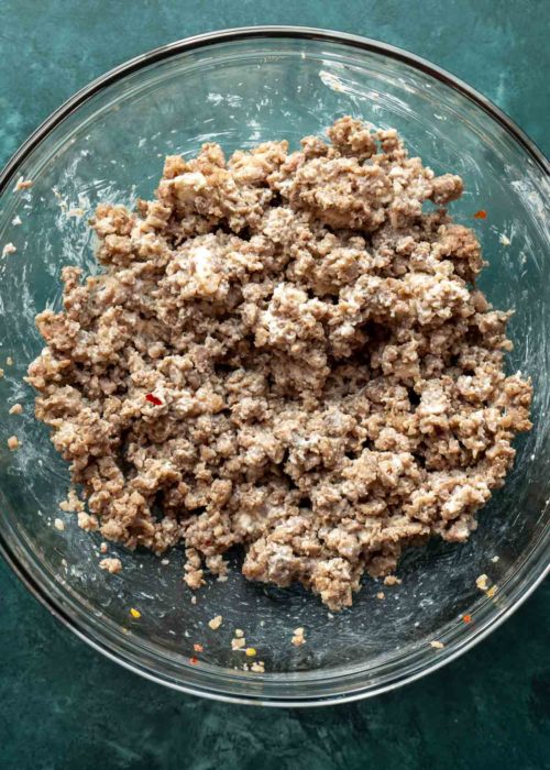 A mixing bowl filled with sausage meat mixed with cream cheese