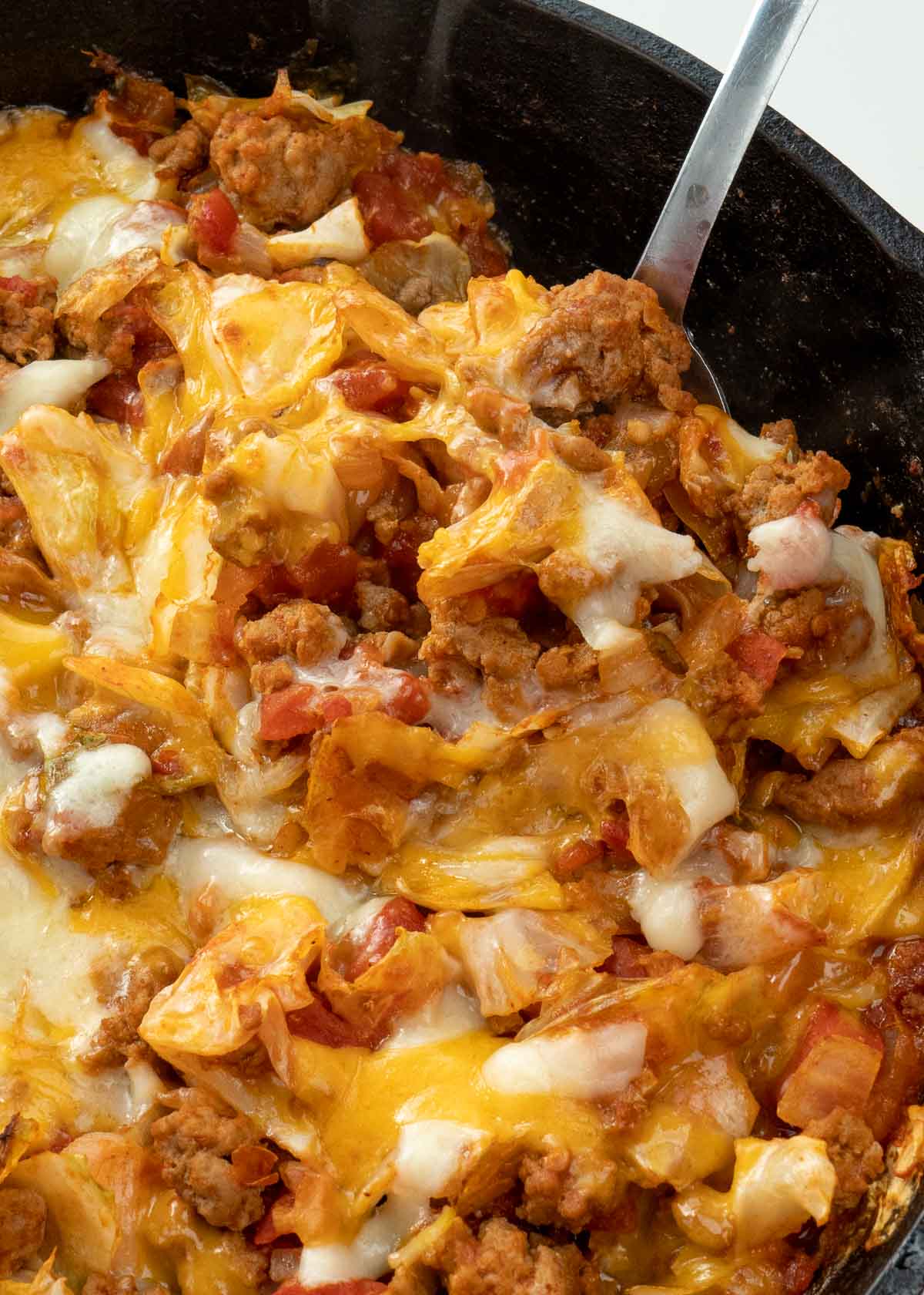 Cabbage and Beef in a tomato sauce with shredded cheese in pan