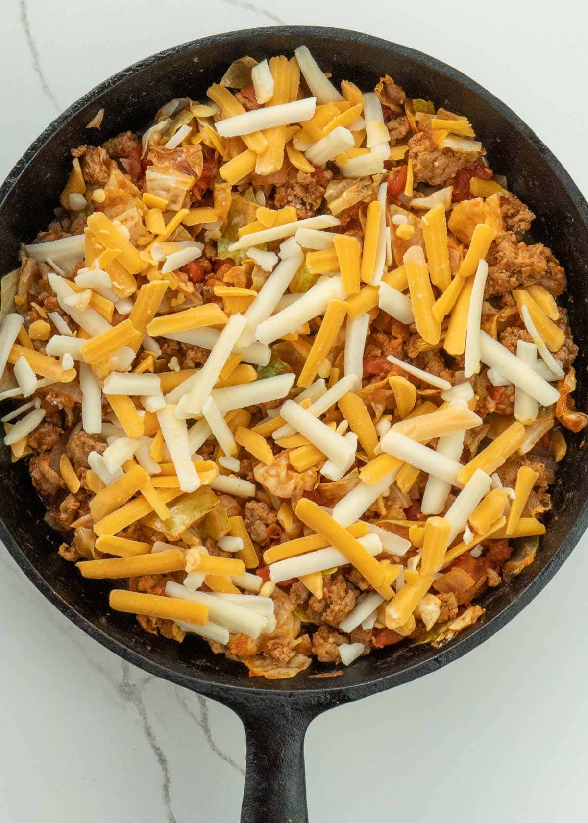 Cabbage and Beef in a tomato sauce with shredded cheese in pan