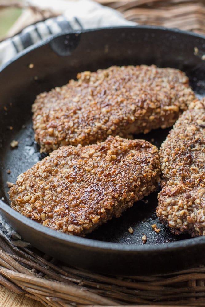 three pecan crusted keto pork chops in a cast iron skillet 