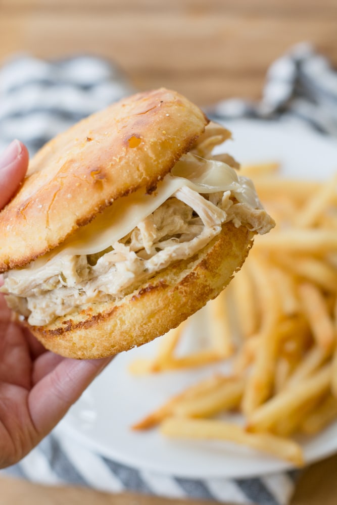 cream cheese ranch chicken sandwiched between an english muffin. The sandwich is being held aloft. 