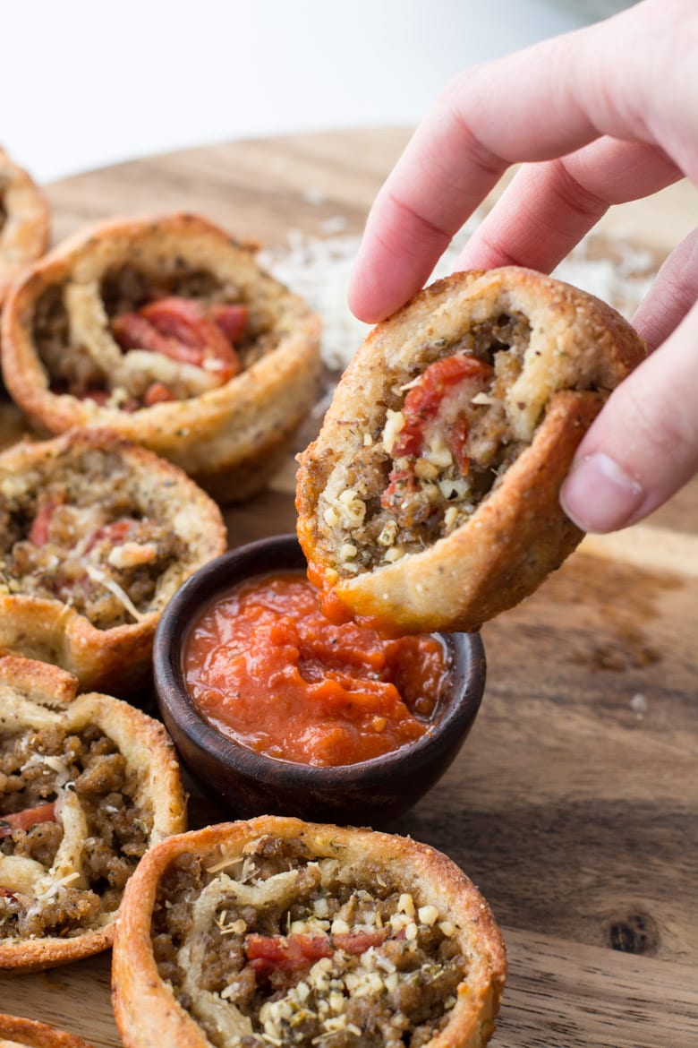 a keto pizza roll up being dunked into marinara sauce 