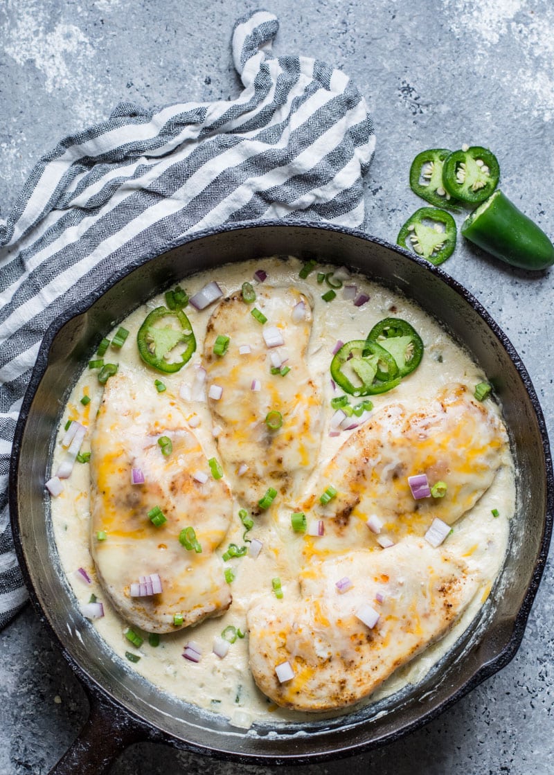 overhead view of four keto jalapeno popper chicken breasts in a cast iron skillet 