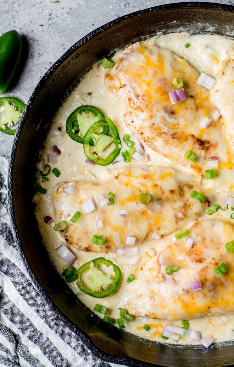 overhead view of three keto jalapeno popper chicken breasts in a cast iron skillet 