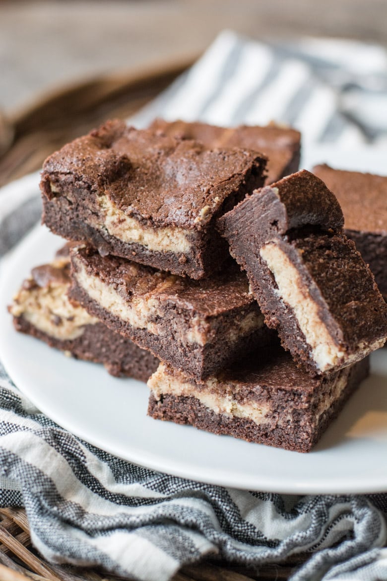 Keto peanut butter cream cheese brownies piled on a white plate 