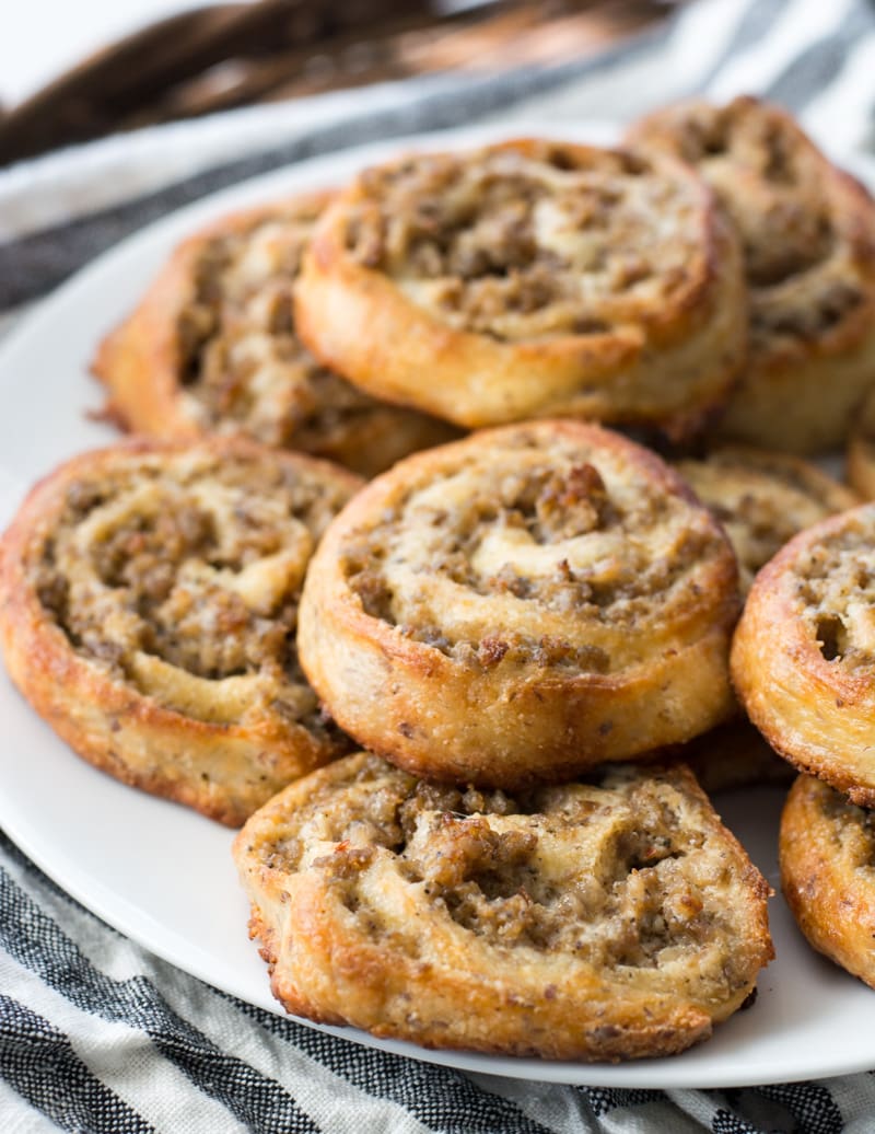 keto sausage pinwheels piled on a white plate 