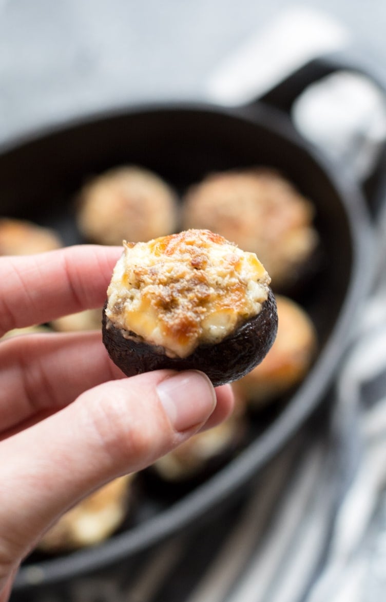 a keto stuffed mushroom being held aloft 