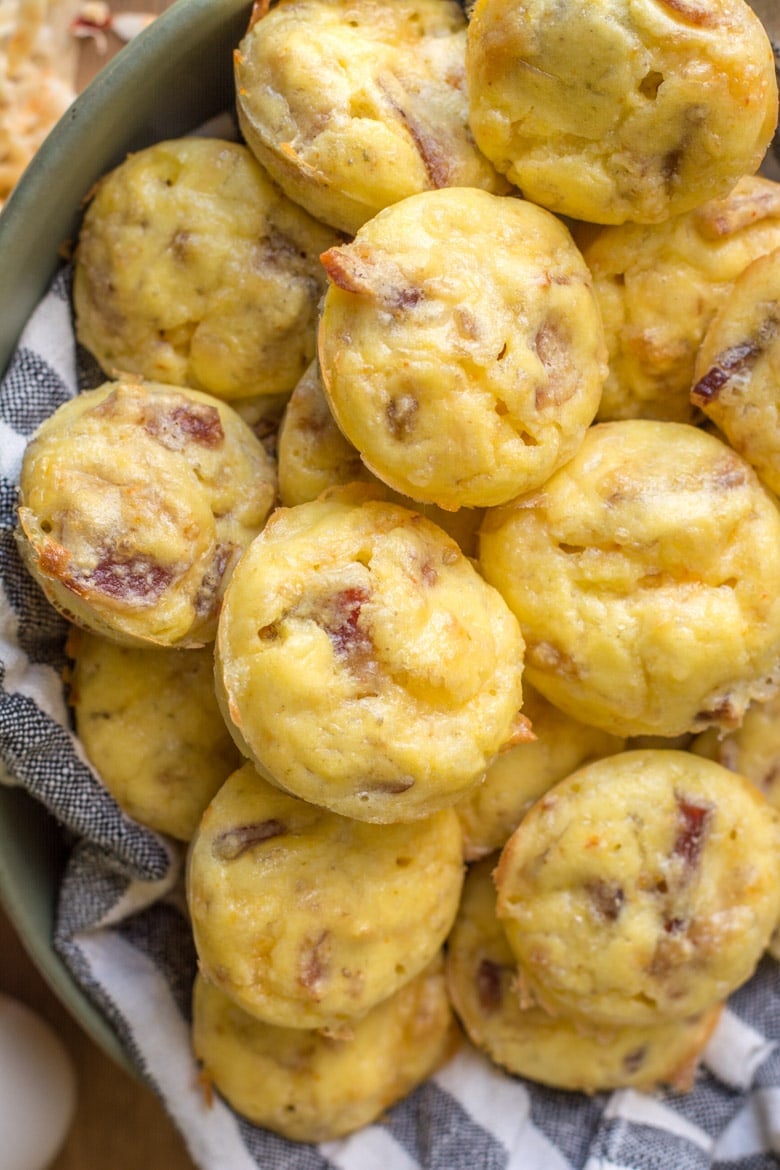 overhead view of bacon and cheese keto egg bites on a towel-lined plate 