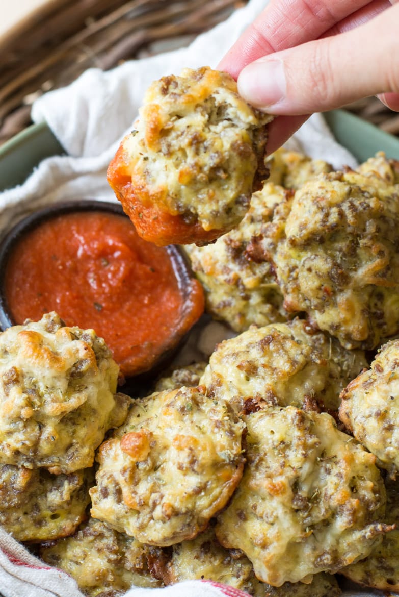 close up of a bowl of keto friendly pizza bites. once bite has just been dunked in marinara 