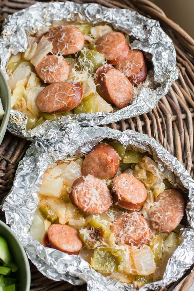 Two cabbage with sausage foil packs on a wicker tray. 
