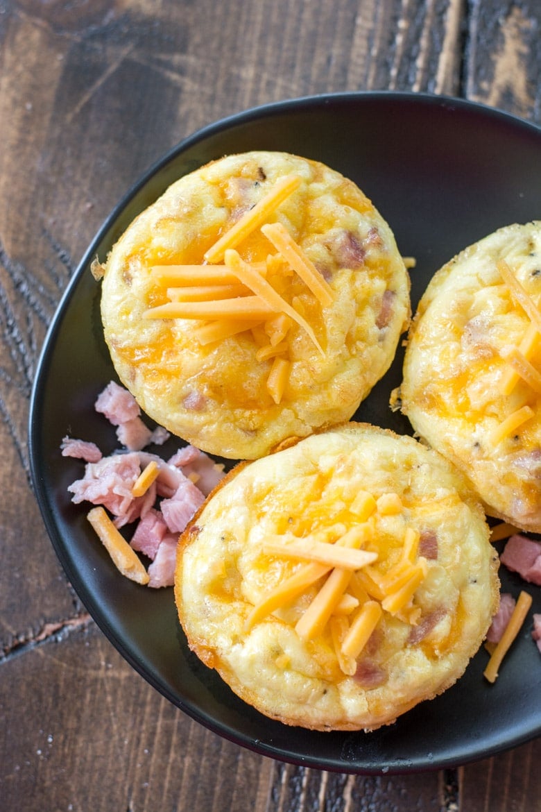 overhead view of three ham and cheese keto egg muffins on a gray plate