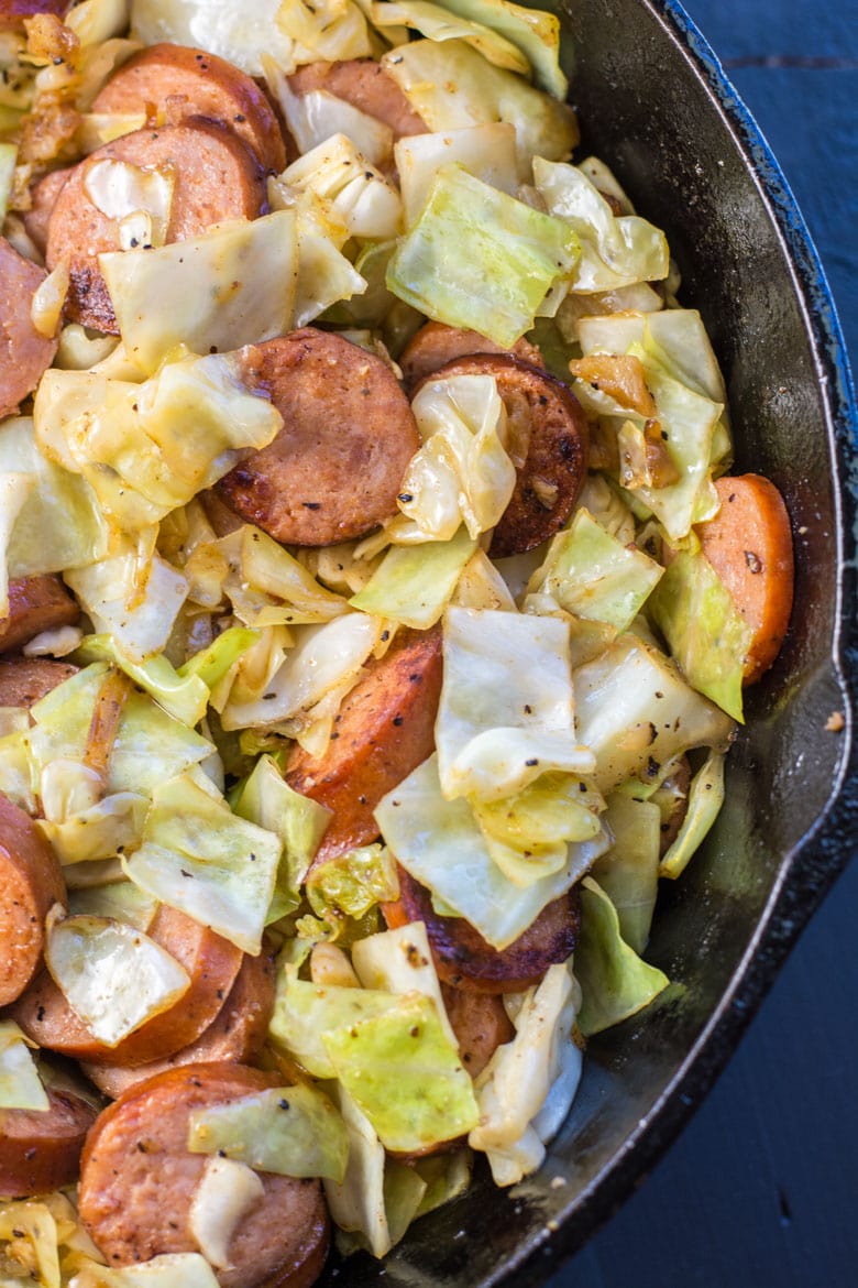 close up of smoked sausage and cabbage in a cast iron skillet 
