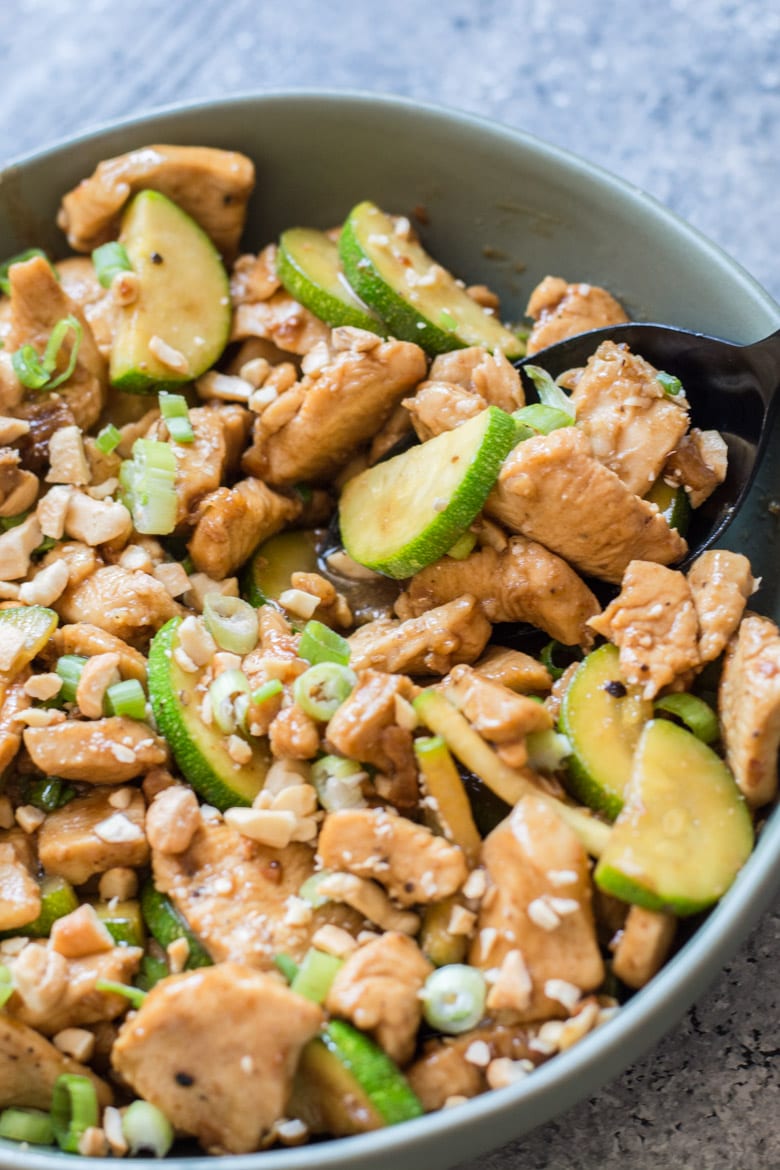 sesame chicken and zucchini keto stir fry in a large gray bowl with a spoon