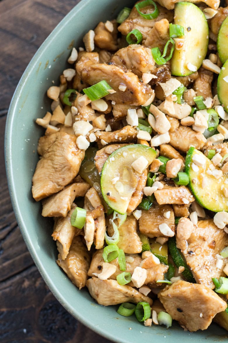 chicken and zucchini low carb stir fry in a bowl, garnished with green onions and cashews 